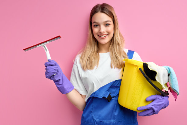 微笑的年轻妇女家庭主妇的肖像，戴着手套，拿着隔离的东西图片下载