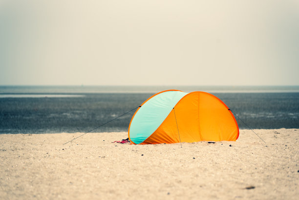 在多云朦胧的天气中，沙滩上的一个单一的帐篷或防风林的中央视图图片下载