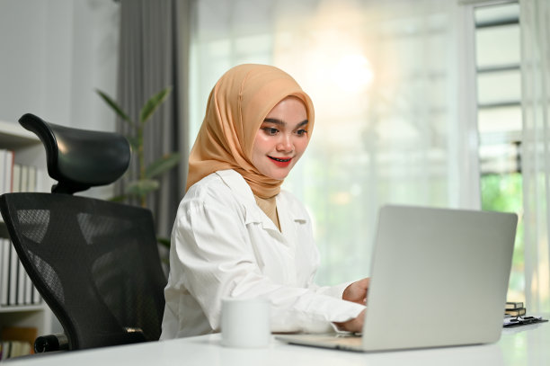 成功的亚洲穆斯林女商人使用笔记本电脑在她的办公桌在办公室。图片下载