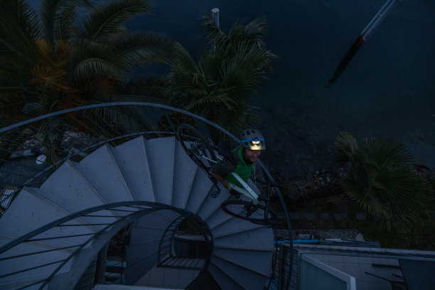 训练结束回家的男子，黄昏时分背着自行车走下楼梯图片下载