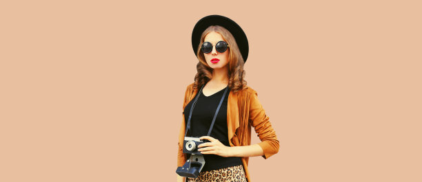 时尚的年轻女子摄影师的肖像与电影相机在棕色的背景图片下载