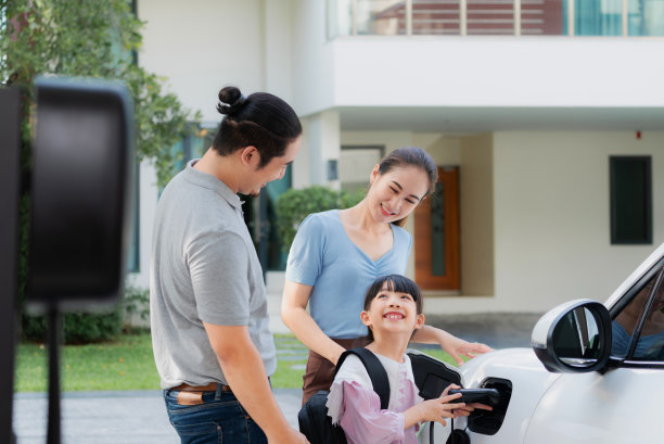 进步的年轻父母和女儿住在一个有电动汽车的家里。图片下载