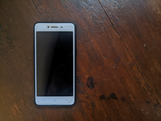 棕色桌子上放着白色智能手机。左侧位置图片下载