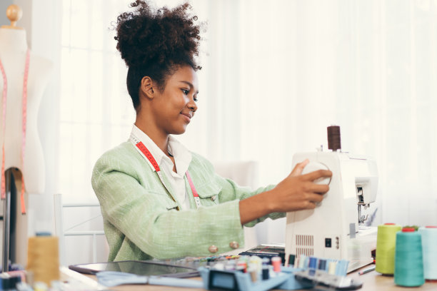 快乐美丽的非裔美国妇女时装设计师的衣服工作与缝纫在自己的服装工作室或精品店图片下载
