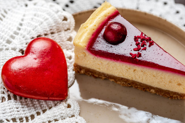 一块樱桃红色慕斯芝士蛋糕和红色心形饼干。情人节图片下载