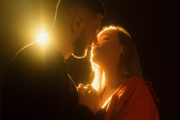 浪漫的情侣在黑暗的房间里对着橙色的灯光接吻图片下载