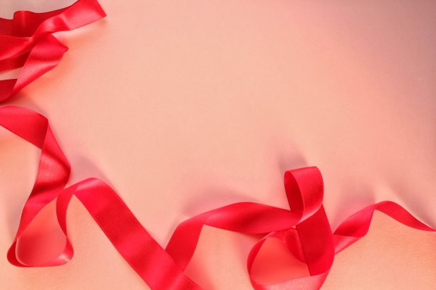 弯曲的波浪绸缎红色缎带在粉红色的背景与复制空间的文本。节日、庆典、周年纪念、生日礼品装饰概念图片下载