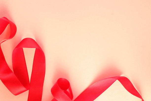 弯曲的波浪绸缎红色缎带在米色背景与复制空间的文本。节日、庆典、周年纪念、生日礼品装饰概念图片下载