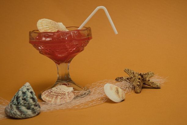 在沙滩上，贝壳搁在渔网上，还有一杯充满冰的夏日清凉饮料图片下载