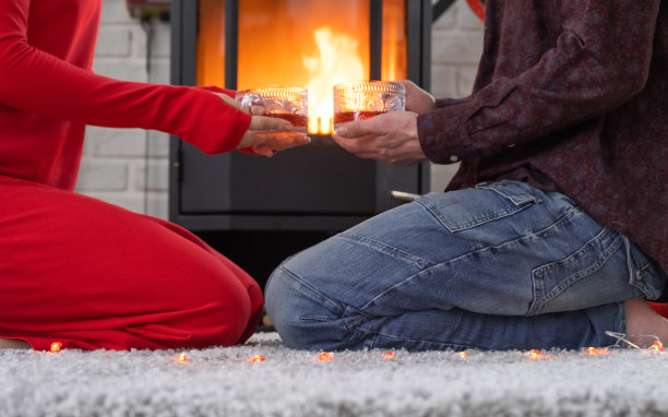 相爱的男女在家里约会，坐在火炉旁，舒适的地毯上燃烧着火焰。情人节，幸福的情侣，爱情故事，人际关系图片下载
