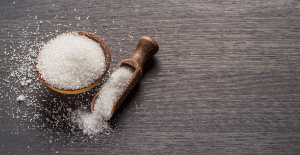 白糖装在木碗里，勺子放在深色木桌上。图片下载