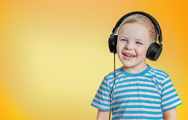 一个快乐的孩子戴着耳机，在橙色的背景上有一个文本的地方图片下载
