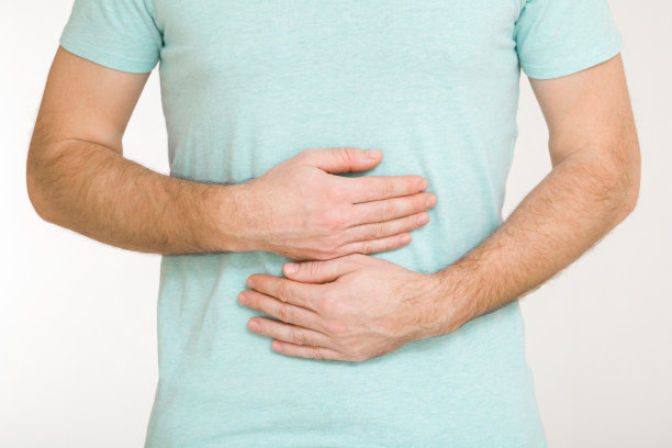 年轻的成年男子触摸疼痛的腹部，手臂孤立在浅灰色背景上。特写镜头。前视图。患有胃痛。图片下载