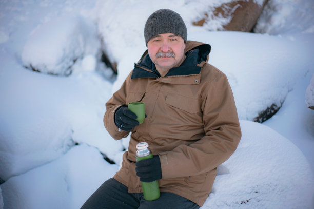 一个人坐在冬天的公园里，手里拿着保温杯，喝着茶、咖啡图片下载