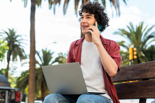 沉思快乐的学生穿着休闲服装坐在长凳上打开笔记本电脑图片下载