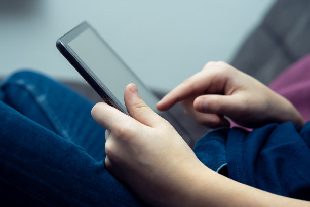 男性手中的数字平板电脑，侧面特写。年轻人在多任务手持设备上工作和打字。图片下载