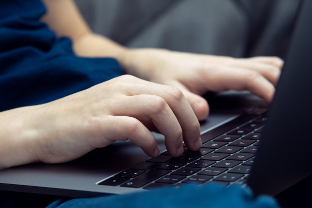 面目全非的男子双手打字，膝盖用笔记本电脑键盘。电子学习和在线学校，编程，编码应用程序图片下载