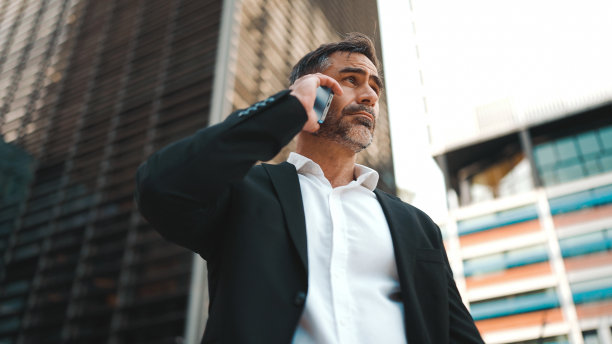 穿着办公服，留着整齐胡子的中年商人正在使用手机。成功男士在智能手机上深情交谈。失望,麻烦图片下载