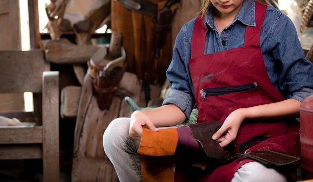 一名妇女在他的车间里处理皮革纺织品废料。图片下载