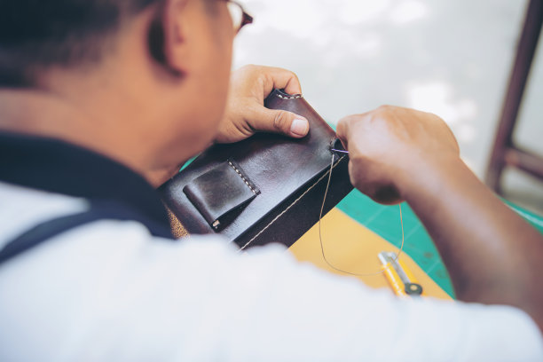 一位有经验的制革工人正在用针脚缝制皮革制品的搭扣。图片下载