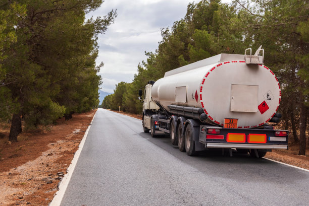 从驾驶位置看，一辆卡车行驶在一条狭窄的道路上，这条道路位于两个挖入地下的切口之间，前景是卡车的仪表盘和方向盘。图片下载