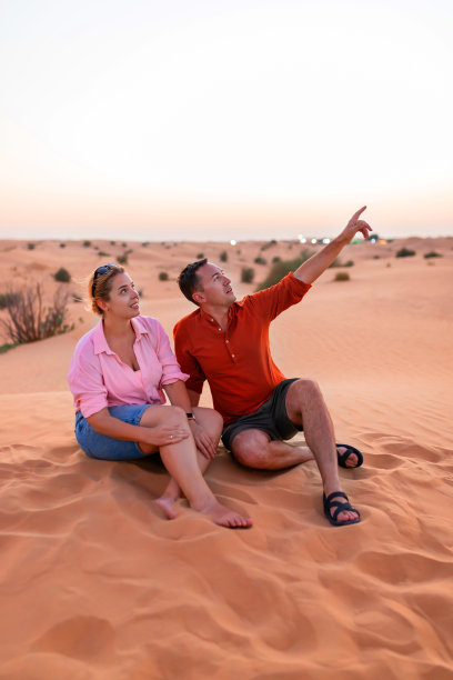 恩爱夫妇坐在沙漠沙丘顶上图片下载