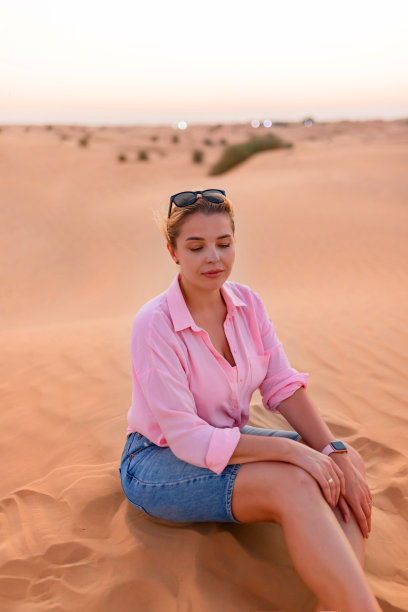 坐在沙漠沙丘上的迷人欧洲女人图片下载