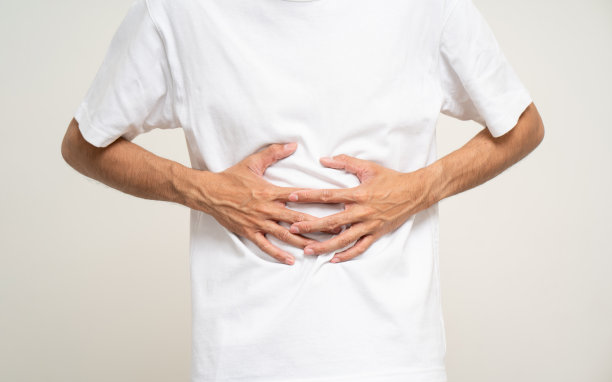 这名男子患有胃痛和胃炎。他把手放在自己的肚子上，捏了捏来放松和安抚他上厕所需要拉屎的时候。在孤立的白色背景上拍摄。图片下载