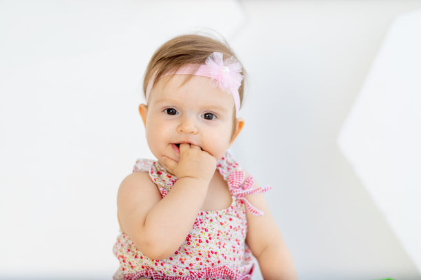 漂亮的肖像小女婴吮吸手指在红色的衣服图片下载