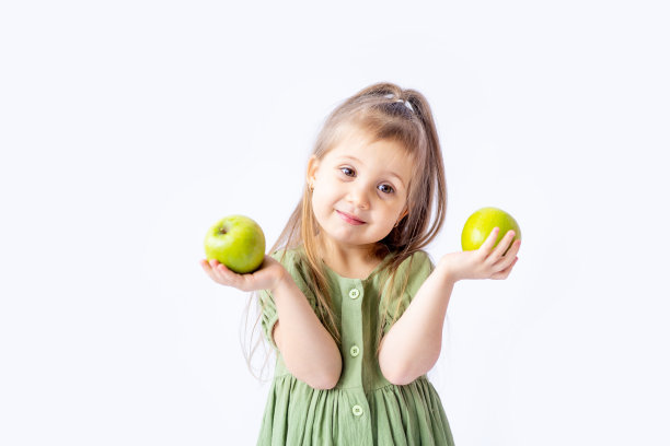 一个可爱的小女孩手里拿着一个大绿苹果。白色隔离背景。儿童健康食品或健康零食。文本空格。高质量的摄影图片下载