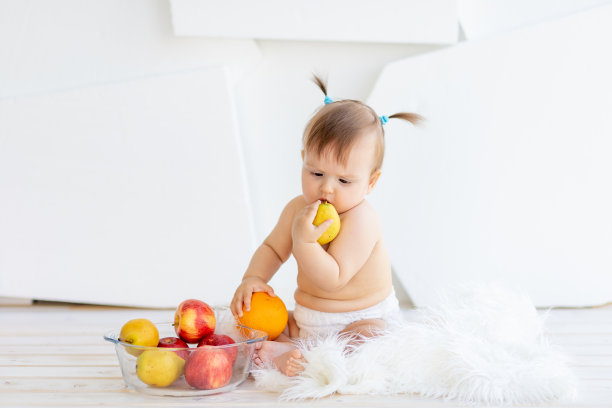 一个小女孩坐在明亮的房间里，手里拿着一盘水果图片下载