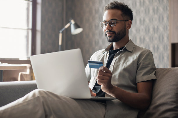 在线支付。年轻人在家里用信用卡使用笔记本电脑图片下载