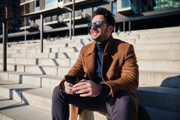 英俊的男人享受阳光明媚的冬天或春天的一天在城市放松在楼梯上图片下载