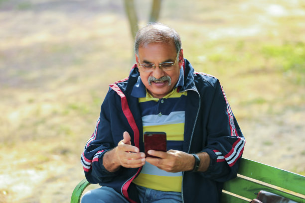 印度老人在公园使用智能手机图片下载