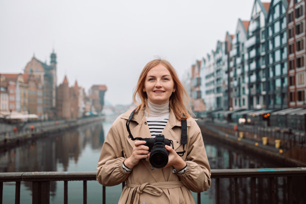 户外微笑的生活方式漂亮的年轻女子在格但斯克，波兰欧洲在晚上与摄影师的相机旅行照片的城市有乐趣的肖像。拍电影的图片下载