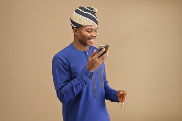 一个年轻的非洲商人用他的智能手机录下了一段语音记录，棕色背景上有一张孤立的肖像图片下载