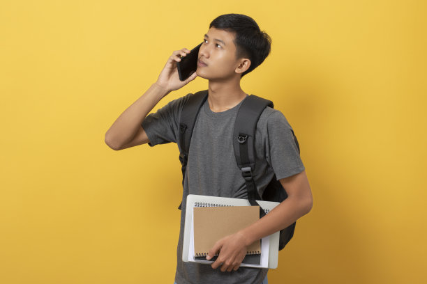 年轻的大学生，书和背包被隔离在黄色背景上图片下载