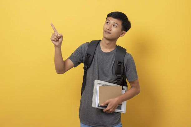 年轻的大学生，书和背包被隔离在黄色背景上图片下载