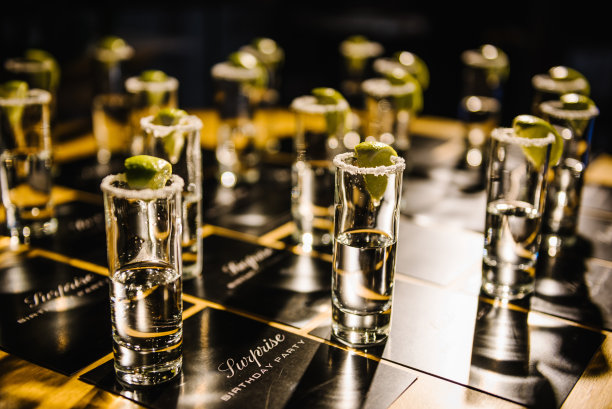 龙舌兰酒。试一试。请坐。惊喜生日派对。许多装有龙舌兰酒、盐和酸橙的玻璃杯放在桌子上招待客人。侧视图。图片下载