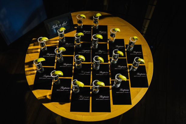 龙舌兰酒。试一试。请坐。惊喜生日派对。许多装有龙舌兰酒、盐和酸橙的玻璃杯放在桌子上招待客人。前视图。图片下载