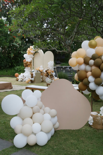 创意中性婴儿淋浴或生日装饰在花园里。波西米亚风格的户外活动设置气球和尖叫板与复制空间。白色奶油桃子焦糖气球拱套件。图片下载