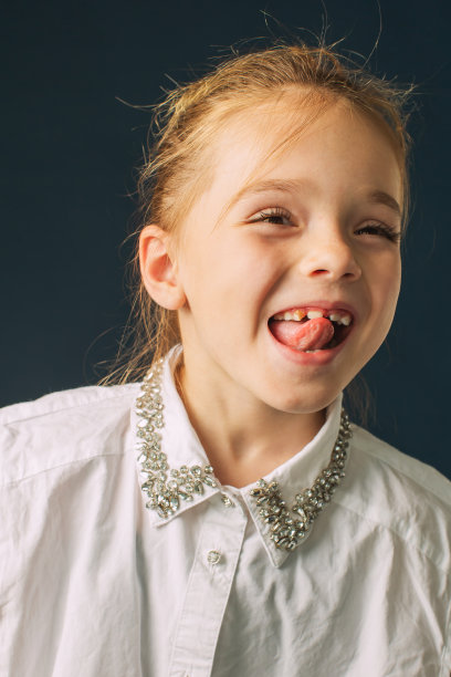 金发女孩在工作室的蓝色背景。的孩子。时尚图片下载