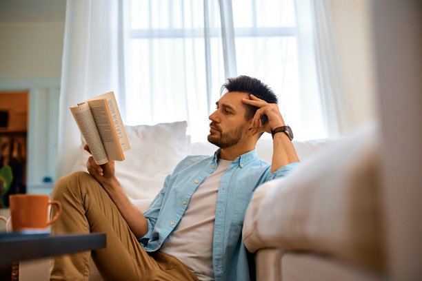 一个男人在客厅里悠闲地看小说。图片下载