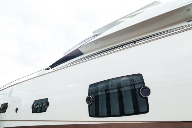 一艘豪华摩托化白色游艇的侧视图，有舷窗和扶手，在蓝天的映衬下。图片下载