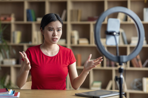 悲伤的严重沮丧的年轻亚洲女士拍摄博客上的智能手机，手势在办公室内部图片下载