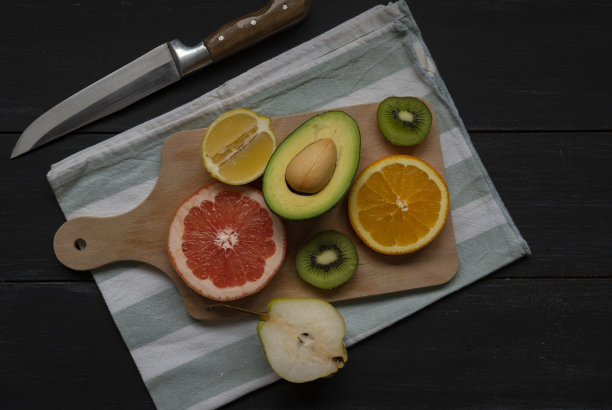 在砧板上用刀把水果和蔬菜切一半作为素食背景图片下载