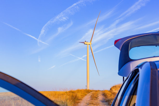在日落时，敞开的树干对着农田里的风力发电厂。五彩缤纷的乡村风光图片下载