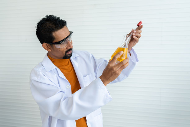 穿着白色白大褂，戴着安全眼镜的男老师正在为大学科学教室里的学生们准备实验工具。 用移液管彻底转移所需体积的化学液体。图片下载