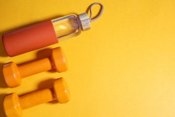 黄色背景上有两个橙色哑铃和水瓶，平铺，留出文字空间图片下载