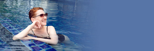 一头红色短发的美女正在泳池里放松图片下载